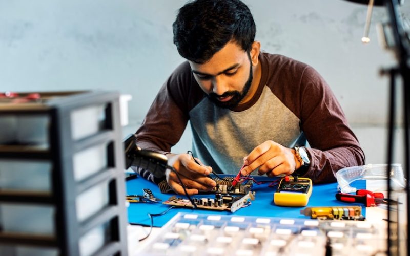technician-using-multimeter-with-computer-electronics-parts_53876-72775